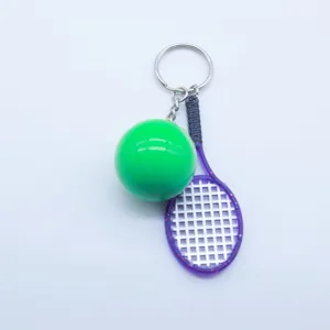 Detailed close-up of mini green bowling ball and purple tennis racket sports keychain