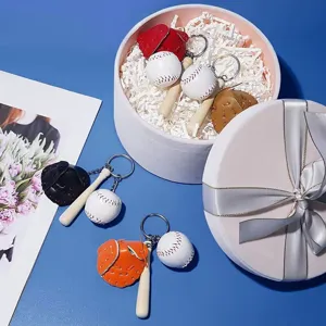 Detail view of multi-colored mini baseball glove and bat keychains in a gift box