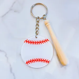 Detailed view of an acrylic baseball keychain with a mini wooden bat on marble.