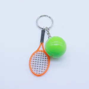 Detailed view of a mini tennis racket and neon ball keychain on a plain white background