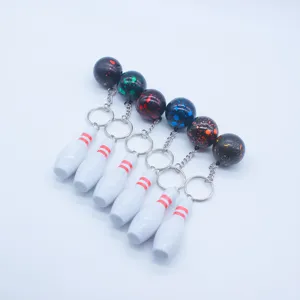 Group of mini bowling pin and colorful splatter ball keychains on white background