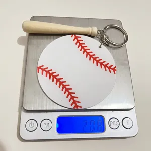 Close-up of acrylic baseball keychain with wooden bat charm showing 20.8g weight on a scale