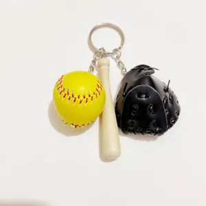 Detail view of a baseball keychain featuring a yellow ball, wood bat, and black glove.