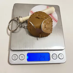 Close-up detail of the baseball glove and bat keychain on a scale showing 24.1g weight