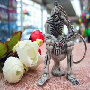 Close-up of a quirky Halloween skeleton sitting on a toilet keychain with a chain.