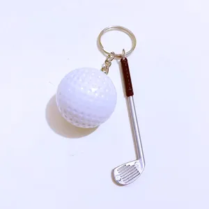 Macro detail of a mini white golf ball and silver club keychain with black grip charm
