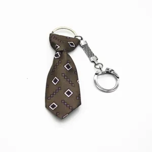 Dettaglio portachiavi mini cravatta marrone con motivo geometrico e anello in argento
