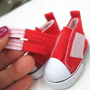 Nahaufnahme eines roten Miniatur-Puppenschuhs aus Stoff mit weißem Klettverschluss.