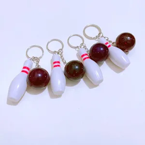 Four-piece mini bowling pin and ball keychain set with red stripes and black finish