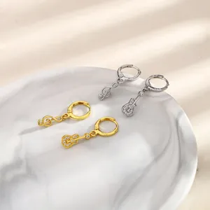 Close-up of asymmetric music note and guitar drop earrings with shiny rhinestones