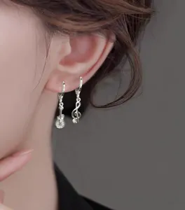 Close-up shot of an Asian model wearing asymmetric silver guitar and music note drop earrings