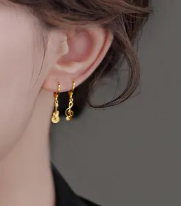 Detailed close-up showing the asymmetric gold guitar and music note earrings with rhinestones