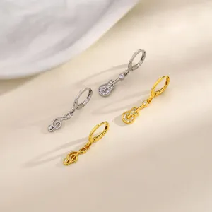 Close-up of asymmetric gold and silver music note and guitar earrings with rhinestones