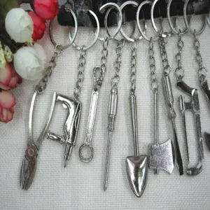 Detailed view of various miniature metal tool keychains including shovel, axe, and pliers.