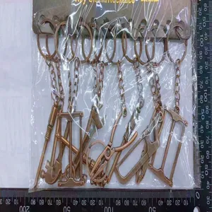 Close-up of vintage bronze tool keychains showing size measurements on a ruler