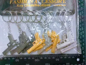 Miniature Beretta 92F metal pistol keychains in gold, silver, and black finish.