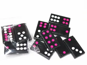 Gros plan de dominos miniatures noirs avec points roses et blancs sous emballage