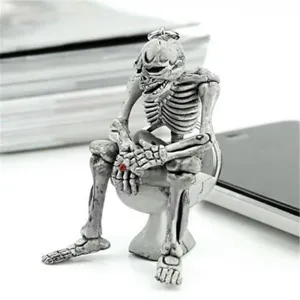 Detailed view of a creative silver skeleton sitting on a white toilet keychain pendant.