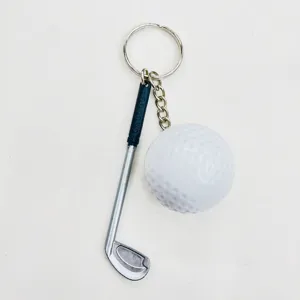 Detailed macro view of a creative miniature golf club and ball keychain on white background.