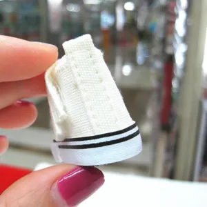 Makroansicht der feinen Nähte an einem 5 cm großen weißen Miniatur-Puppen-Turnschuh