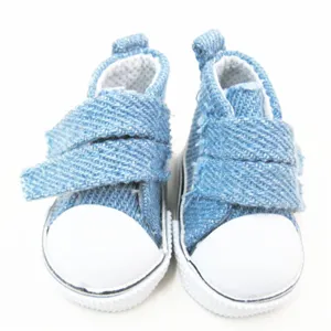 Makroaufnahme von 5cm hellblauen Denim-Puppenschuhen aus Segeltuch mit Gummikappe.