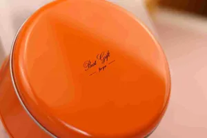 Caja redonda de hojalata naranja para galletas y snacks con elegante diseño de regalo.