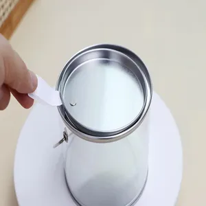 Vista dettagliata della scatola regalo trasparente in PVC e latta con manico in metallo.