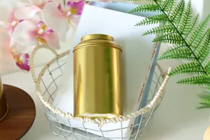 Close-up detail shot of a shiny gold tinplate tea canister placed in a decorative wire basket.