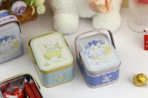 Détail de boîte en fer blanc portable avec illustration de lapin et poignée en métal.