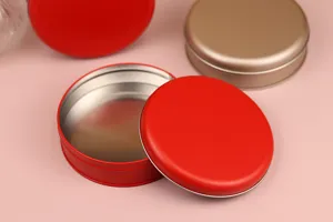 Gros plan de détail sur des boîtes d'emballage rondes en fer-blanc de couleur rouge et dorée.