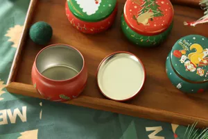 Gros plan de boîtes de rangement rondes de Noël en métal avec des motifs mignons sur plateau.
