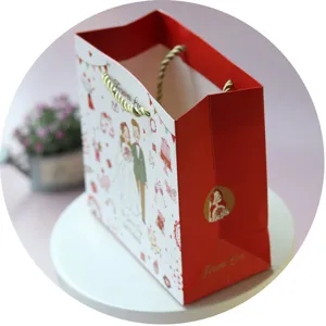 Sac cadeau en papier rouge pour mariage avec charmante illustration des mariés et anses.