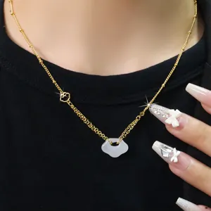 Macro di una collana in oro con un ciondolo a forma di lucchetto in calcedonio bianco puro