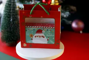 Coffret cadeau rectangulaire en fer-blanc de Noël avec sac en papier rouge, détail emballage biscuits.