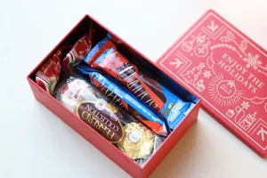 Boîte cadeau en métal rectangulaire de Noël remplie de chocolats et de friandises.