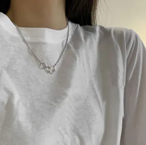 Detailansicht einer minimalistischen, hohlen Herz-Halskette aus Silber auf weißem T-Shirt
