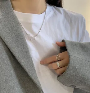 Nahaufnahme einer modischen silbernen Herzkette und Ringen mit grauem Blazer