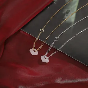 Dettaglio di eleganti collane tradizionali con ciondoli Ruyi in calcedonio bianco, oro/argento.