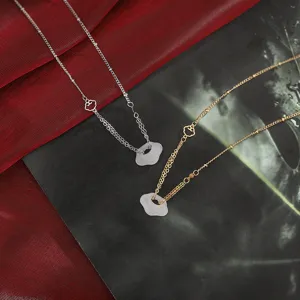 Dettaglio macro di ciondoli serratura a nuvola in calcedonio bianco su catene oro e argento