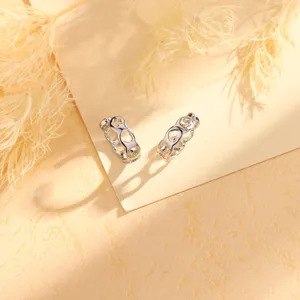 Detalle de pendientes de plata con patrones de estrellas y corazones, sin agujero.