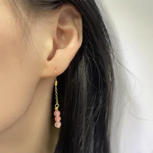 Nahaufnahme eleganter rosa Erdbeerkristall-Ohrringe mit Goldquaste und Ohrhaken