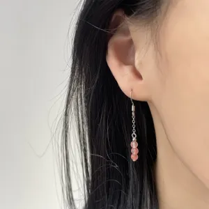 Nahaufnahme eines eleganten rosa Erdbeerquarz-Ohrring-Anhängers am Ohr mit Silberhaken