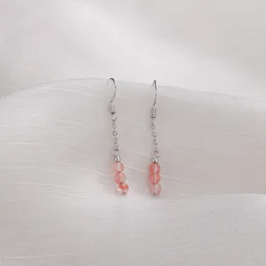 Nahaufnahme von eleganten rosa Erdbeerquarz-Ohrhängern mit silbernen Haken und feinen Ketten.