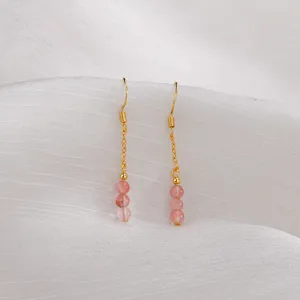 Nahaufnahme der rosa Erdbeerkristallperlen an eleganten goldenen Quastenohrringen