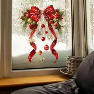Red Christmas bow window sticker with ornaments displayed on glass against snowy scene