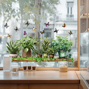 Detailed view of green plant and butterfly electrostatic window stickers on a glass surface