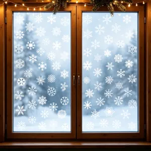 Dettaglio di vari adesivi statici a forma di fiocco di neve bianca su una finestra di legno