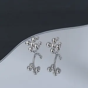 Macro view of silver cross bead ear cuffs with clear reflection on a wave-shaped mirror.