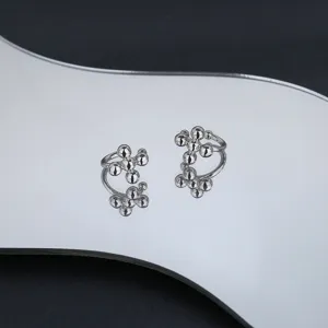 Detailed view of silver cross round bead ear cuffs shown on a reflective mirror