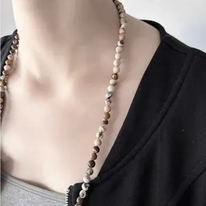 Detailweergave van een natuurlijke zebra-stenen kralenketting gedragen door model